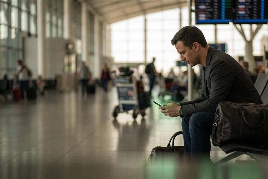 Persona en una terminal de aeropuerto usando el celular